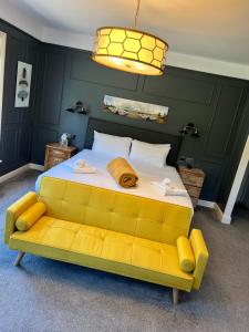 a bedroom with a large bed with a yellow couch at The Plough Inn in Marsham