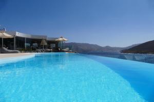 a large blue swimming pool with a view of the water at Panormos Village Hotel in Mykonos