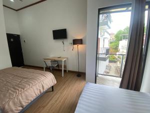 ein Schlafzimmer mit Bett, Schreibtisch und Fenster in der Unterkunft EMWEKA Residence Balikpapan in Balikpapan