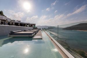 a infinity pool with a view of the water at Panormos Village Hotel in Mykonos
