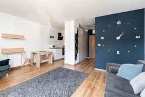 ein Wohnzimmer mit einem Sofa und einer Wand mit einer Uhr in der Unterkunft Prokocim Blue Studio in Krakau