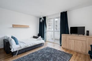 ein Wohnzimmer mit einem Bett und einem Flachbild-TV in der Unterkunft Prokocim Blue Studio in Krakau