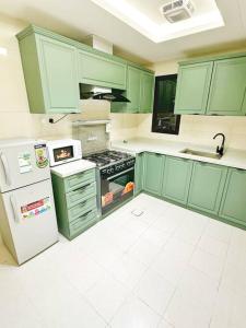 a kitchen with green cabinets and a stove and refrigerator at شقة بغرفتين نوم وبلكونة خاصة ١٥ in Riyadh