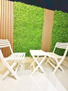 twee witte stoelen naast een groene muur bij شقة بغرفتين نوم وبلكونة خاصة ١٥ in Riyad