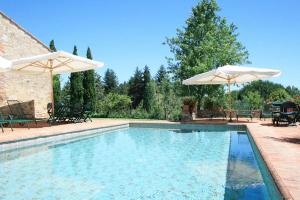 una piscina con 2 sombrillas y sillas blancas en Agriturismo Monacianello - Fontebelvedere wine estate en Ponte A Bozzone