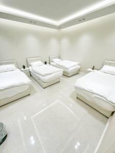 drie bedden in een witte kamer met witte vloeren bij شقة بغرفتين نوم وبلكونة خاصة ١٥ in Riyad