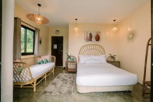 a bedroom with a white bed and a couch at Samkara Restaurant and Garden Resort in Majayjay