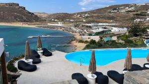 a pool with chairs and umbrellas next to a beach at Panormos Village Hotel in Mykonos