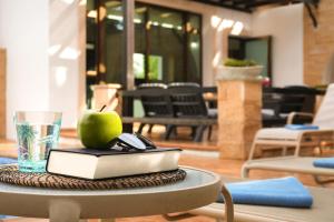 een appel zittend op een tafel met een boek en een glas bij Villa Anthia - 2bed with Large Pool in Ayia Napa