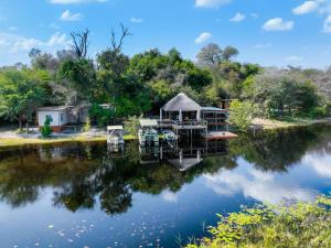una casa su un fiume con il suo riflesso nell'acqua di Mukolo Cabins & Camping a Kongola