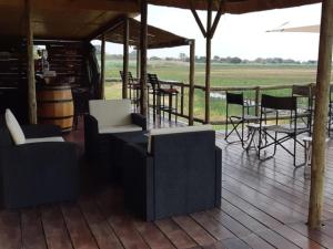 a porch with chairs and tables and a barrel at Mukolo Cabins & Camping in Kongola