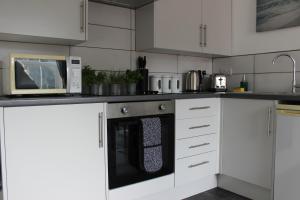 uma cozinha com armários brancos e uma máquina de lavar louça preta em Oliver Wests Beautiful 1 Bedroom Retreat em Scarborough