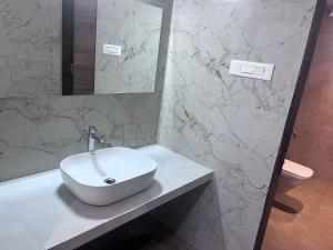 lavabo blanco en la encimera del baño en Triveni Stays The Bliss, en Satara