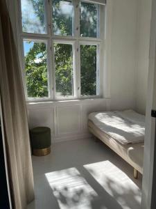 a white room with a bed and two windows at Luxurious apartment by Royal palace in Oslo