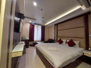 a bedroom with a large white bed with red pillows at New Gitanjali Hotel, New Digha in Digha