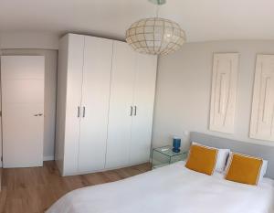 ein Schlafzimmer mit weißen Schränken und einem Bett mit zwei orangenen Kissen in der Unterkunft Bautiful and centrally located, Cuzco-Bernabeu in Madrid