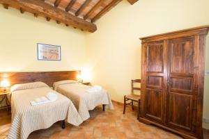 Cette chambre comprend 2 lits et une armoire en bois. dans l'établissement Agriturismo Monacianello - Fontebelvedere wine estate, à Ponte A Bozzone