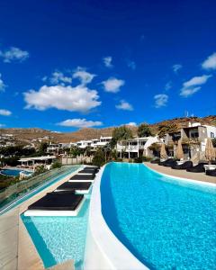a pool at a resort with blue water at Panormos Village Seaside Resort in Mykonos