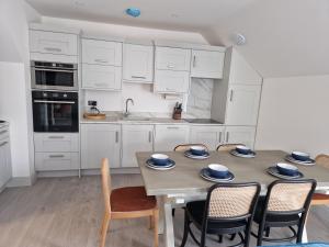 una cocina con armarios blancos y una mesa con sillas. en Beach Penthouse, Hunstanton Norfolk, en Hunstanton