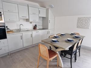 una cocina con armarios blancos y una mesa de madera con sillas. en Beach Penthouse, Hunstanton Norfolk, en Hunstanton
