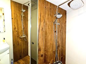eine Dusche im Bad mit einer Holzwand in der Unterkunft Apartament Moniuszki Starówka Bytom 40m2 in Bytom