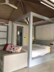 um quarto com uma cama alta e um sofá em Baan Bangrak Garden em Koh Samui