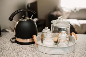 a tray with a tea kettle and glass jars on a counter at Die Karee Tuiste in Postmasburg