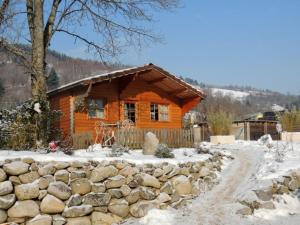 a log cabin in the snow with a stone wall at Le Repaire de Mitzerlé in Mitzach