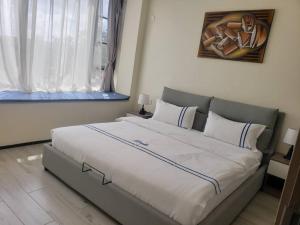ein großes Bett in einem Schlafzimmer mit Fenster in der Unterkunft GolfHill Apartment in Kigali
