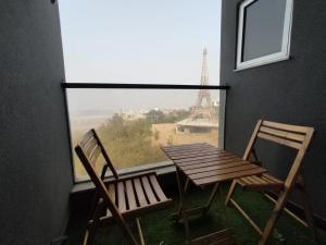two chairs and a wooden table and a window with the eiffel tower at Royal Reside in Rawalpindi