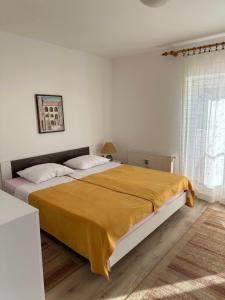 Apartment & Apartment Studio Deželjin في سينج: غرفة نوم بسرير كبير مع بطانية صفراء