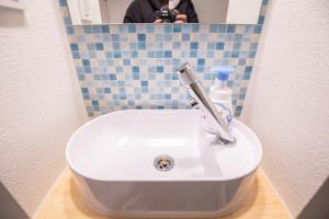 una persona que toma una foto de un lavabo en un baño en 2min walk to Higashi Shinjuku Sta SiEW, en Tokio