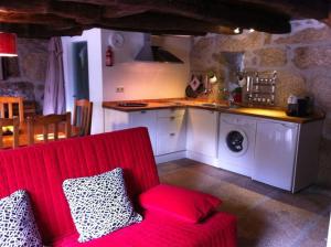 a living room with a red couch and a kitchen at Eira das Carvalhas in Penafiel