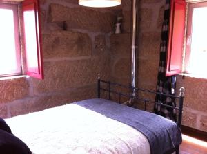 um quarto com uma cama numa parede de pedra em Eira das Carvalhas em Penafiel