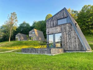 a barn style house on a grassy field at Domki 4 Nad Ranem - Baza Bieszczady Smerek in Wetlina