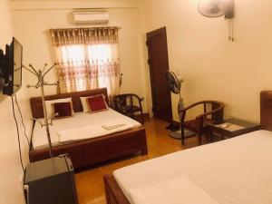 a bedroom with a bed and two chairs and a window at Nhà nghỉ 1061 in Hai Phong