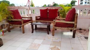 2 stoelen met rode kussens en een tafel op een balkon bij ZARADISE SUITES HOTEL, MOMBASA KENYA in Mombasa