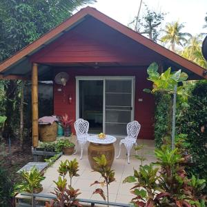 a red cottage with a table and chairs on a patio at Pink Kangaroo Bungalows in Ko Kood