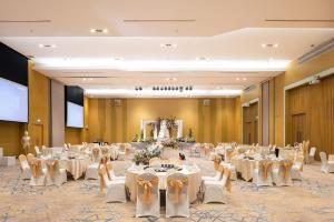 The Idle Hotel and Residence - SHA Plus Certified في محافظة باثوم ثاني: قاعة احتفالات مع طاولات وكراسي في غرفة