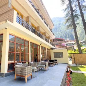 a building with a patio with tables and chairs at Pinewood by Offlimits Homes in Kasol