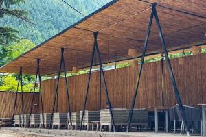a pavilion with chairs and tables and a wooden wall at Pinewood by Offlimits Homes in Kasol