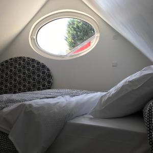 Schlafzimmer mit einem Bett und einem runden Fenster in der Unterkunft charmante maisonnette in Le Havre