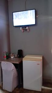 a television hanging on a wall above a desk with a refrigerator at dunduzu village lodge in Mzuzu
