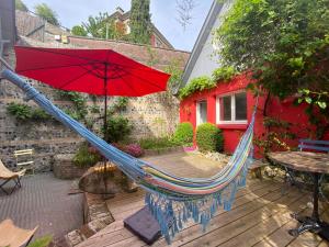 eine Hängematte mit einem roten Regenschirm auf einer Terrasse in der Unterkunft charmante maisonnette in Le Havre