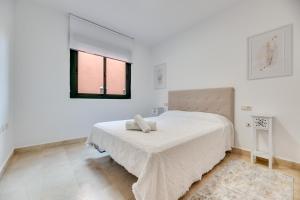 Un dormitorio blanco con una cama y una ventana. en Cabopino, cerca de todo, en Marbella 14 fotos más