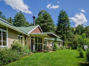 dom z ogródkiem z zieloną trawą w obiekcie Ondini Cottage w mieście Drakensberg Garden