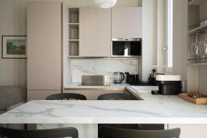 a kitchen with white cabinets and a table with chairs at Santa Tecla Living Certosa 133 in Milan