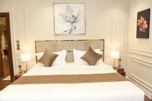 una camera da letto con un grande letto bianco con cuscini di Rose Bark - روز بارك a Hafr Al Baten