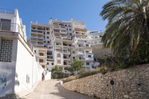 a large white apartment building next to a stone wall at Estupendo Apartamento Mediterráneo in Faro de Cullera