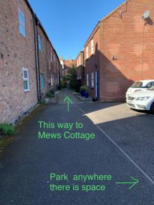 a parking lot with a car parked next to a brick building at The Mews Cottage, with parking, Yarm in Yarm